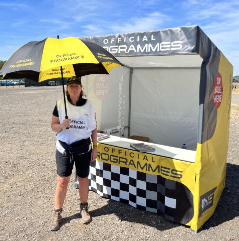 A woman with an umbrella outside a kiosk